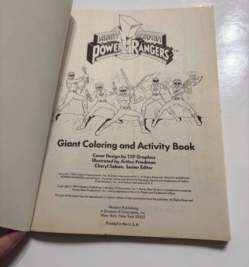May include: A black and white coloring book cover featuring the Mighty Morphin Power Rangers characters. The cover text reads "Giant Coloring and Activity Book".