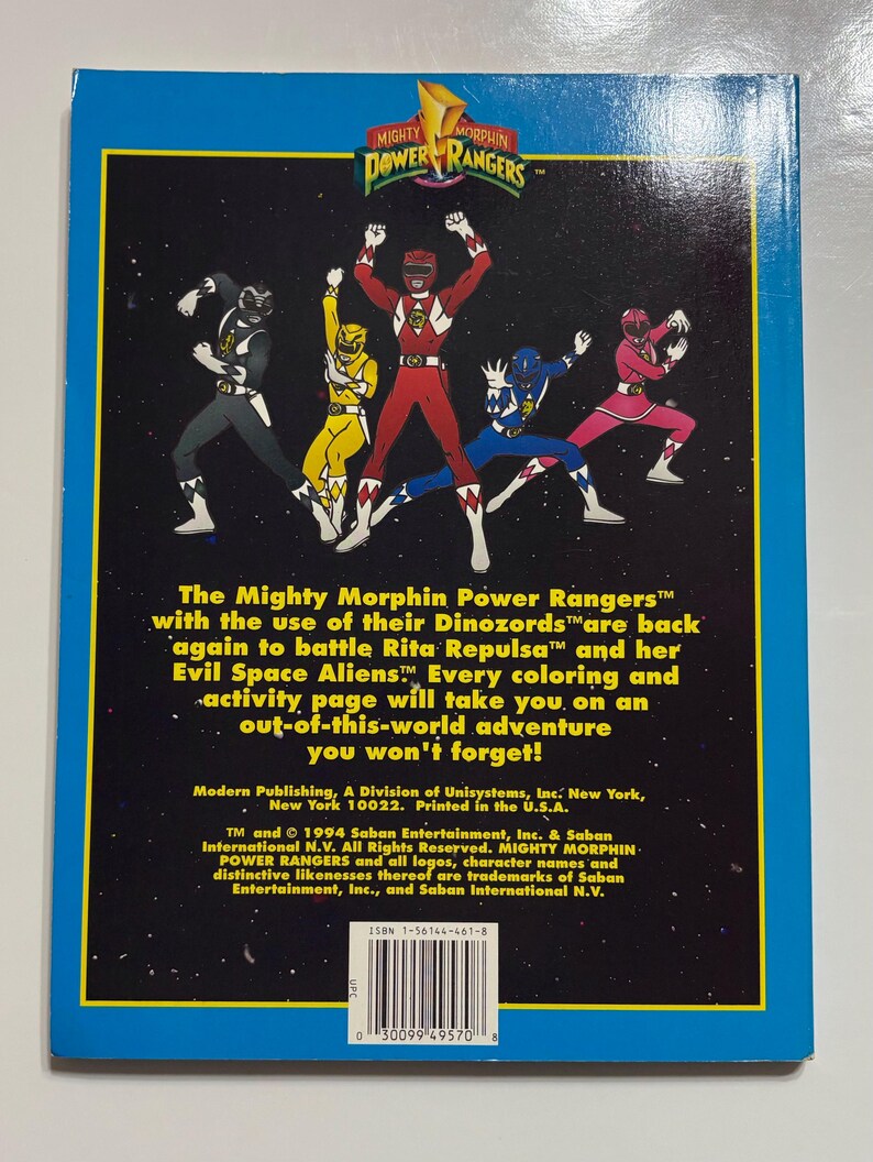 May include: The Mighty Morphin Power Rangers coloring book cover features a group of five Power Rangers in their colorful suits, standing in a fighting pose against a black starry background. The text "Mighty Morphin Power Rangers" is in a blue box at the top of the cover.