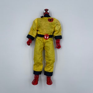 Puede incluir: Una figura de acci&oacute;n de Spider-Man de color amarillo y rojo que lleva un mono amarillo con un cintur&oacute;n negro y un logotipo de ara&ntilde;a en el pecho. La figura tiene la cabeza roja y los ojos negros.