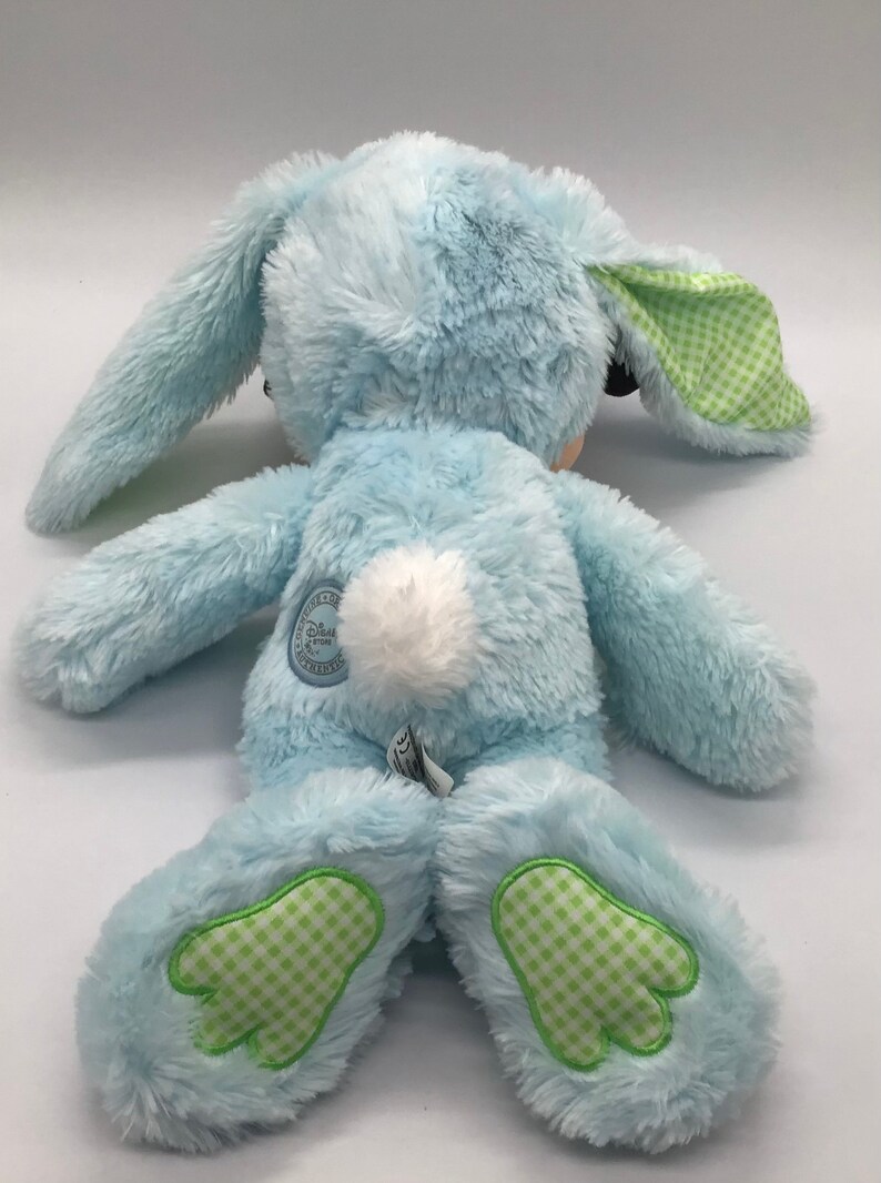 K&ouml;nnte beinhalten: Ein blauer Pl&uuml;schhase mit gr&uuml;n-wei&szlig; karierten Ohren und F&uuml;&szlig;en. Der Hase hat einen wei&szlig;en, flauschigen Schwanz und ein Disney Store-Etikett auf dem R&uuml;cken.