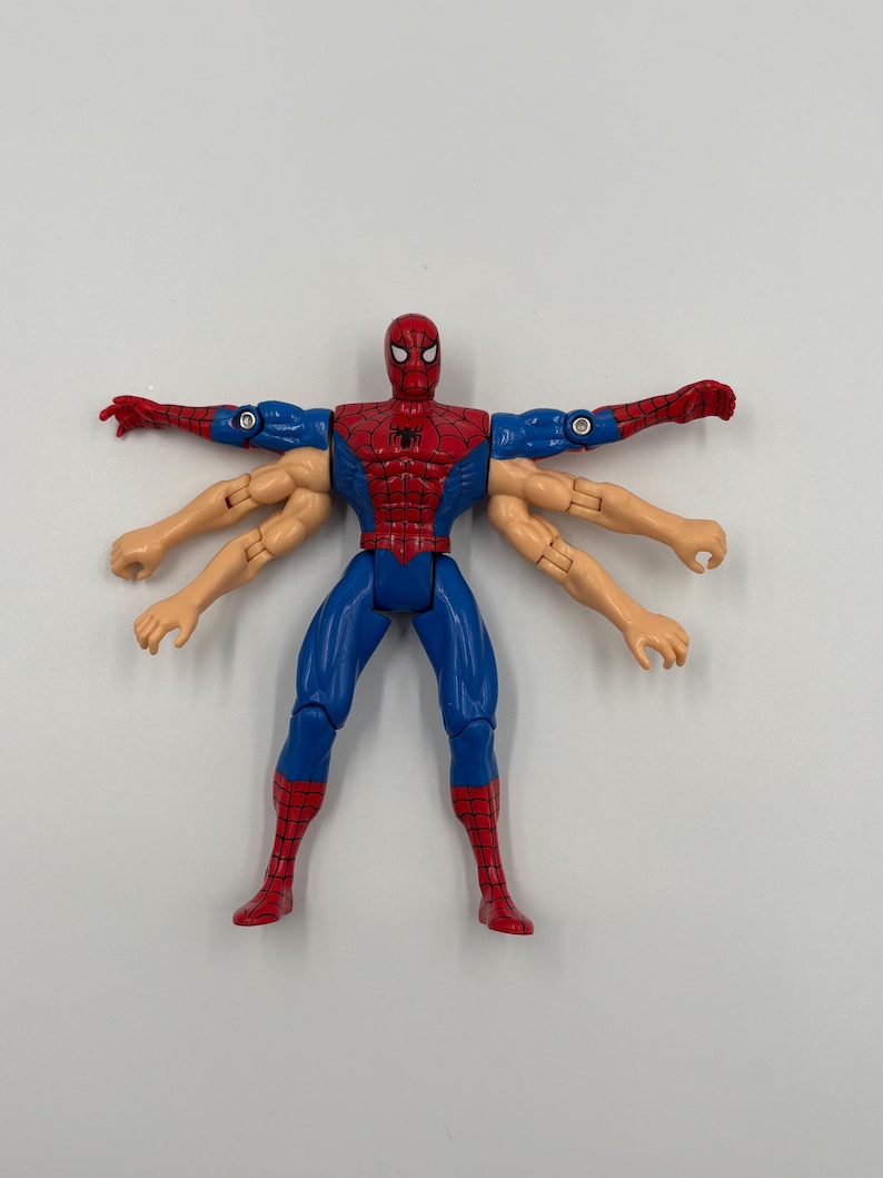 May include: A Spider-Man action figure with six arms, in a classic red and blue costume. The figure has a detailed design, with a spider emblem on the chest and red boots. The figure is posed with arms outstretched.
