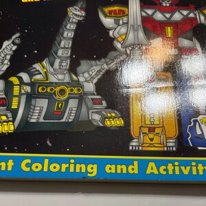 May include: A coloring and activity book featuring the Power Rangers. The cover shows a black and yellow robot with a red and silver robot in the background. The book has a blue border with the text "Giant Coloring and Activity" on the bottom.