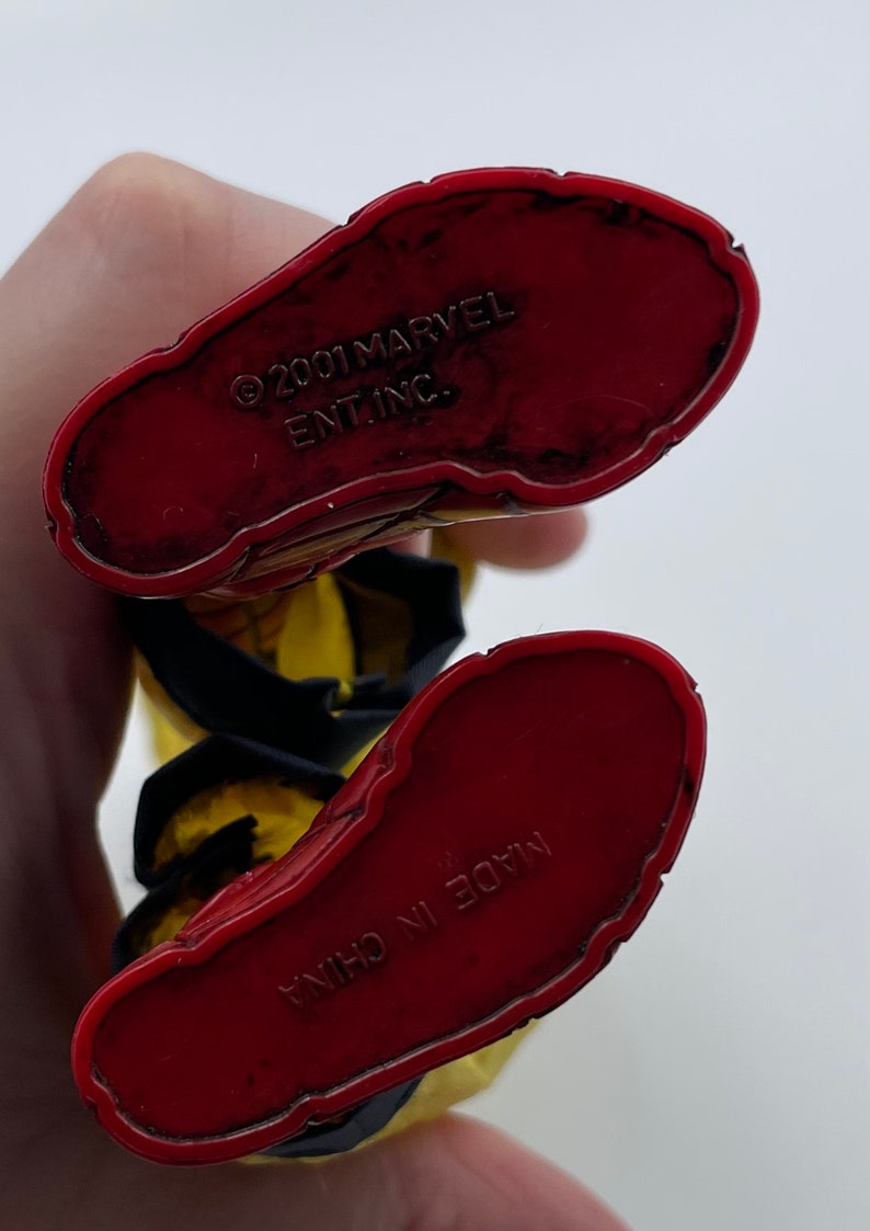 Puede incluir: Primer plano de la parte inferior de una figura de acci&oacute;n roja y amarilla. Los pies de la figura son rojos y tienen el texto "&copy;2001 MARVEL ENT. INC." y "MADE IN CHINA" impreso en ellos.