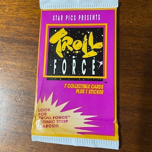 May include: A purple and yellow card pack with the text "STAR PICS PRESENTS Troll FORCE™" and "7 COLLECTIBLE CARDS PLUS 1 STICKER". The pack also has the text "LOOK FOR TROLL FORCETM COMIC STRIP CARDS!!!".