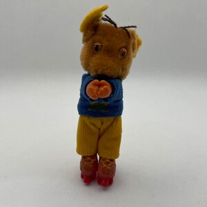 May include: A brown plush toy mouse wearing a blue sweater and yellow pants, with orange hands and red roller skates.