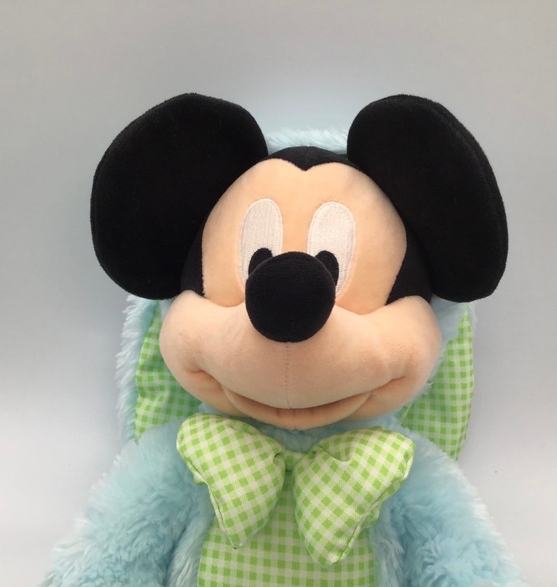 K&ouml;nnte beinhalten: Ein blauer Pl&uuml;sch-Mickey Mouse mit einer gr&uuml;n-wei&szlig; karierten Schleife. Das Pl&uuml;schtier ist in ein blaues Hasenkost&uuml;m mit einem gr&uuml;n-wei&szlig; karierten Kragen gekleidet.