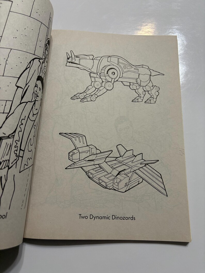 May include: Black and white line art illustration of two robot dinosaurs. The first robot dinosaur is a quadruped with a long tail and a horn on its head. The second robot dinosaur is a flying robot with two sets of wings. The text "Two Dynamic Dinozords" is printed below the illustrations.
