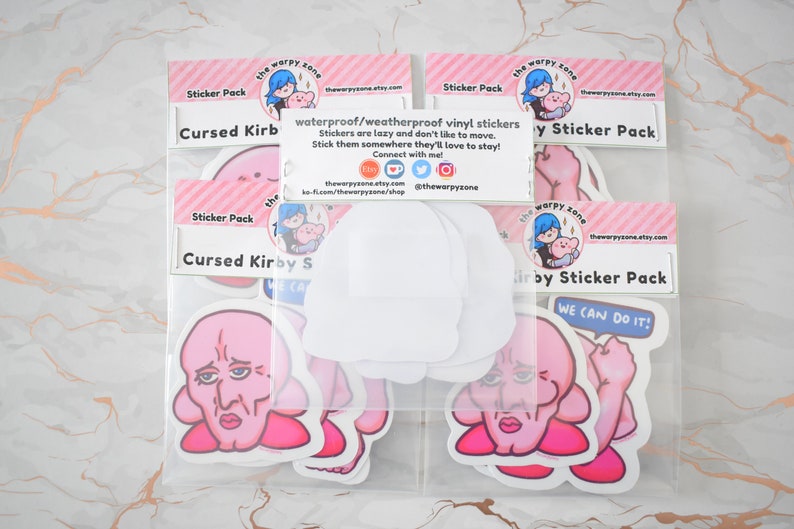 Pu&ograve; includere: Un set di quattro pacchetti di adesivi con un personaggio rosa di Kirby con un viso umano. I pacchetti di adesivi sono etichettati "Cursed Kirby" e "Kirby Sticker Pack". Gli adesivi sono impermeabili e resistenti alle intemperie.