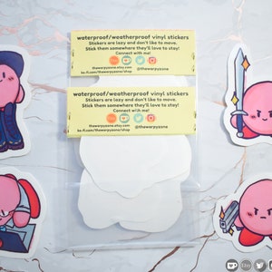 Pu&ograve; includere: Un set di cinque adesivi in ​​vinile impermeabili che mostrano un personaggio rosa con diverse espressioni e accessori. Gli adesivi sono confezionati in un sacchetto di plastica trasparente con un'etichetta gialla che recita "adesivi in ​​vinile impermeabili/resistenti alle intemperie" e include i dati di contatto del venditore.