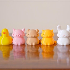 Peut inclure: Un ensemble de neuf figurines d'animaux imprim&eacute;es en 3D. Les figurines sont de diff&eacute;rentes couleurs, notamment le blanc, le jaune, le rose, le marron, l'orange et le noir. Les animaux comprennent un canard, un cochon, un ours, un chat, un lapin et un oiseau.