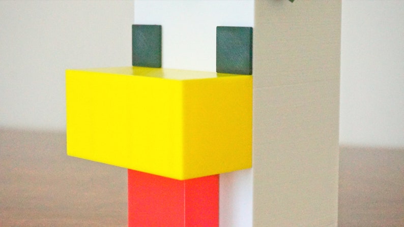 May include: A white, yellow, and red block toy shaped like a chicken. The chicken has black eyes and a yellow beak.