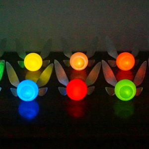 May include: Ten glowing fairy lights in various colors, including white, green, blue, yellow, red, and purple. Each light has a pair of wings.