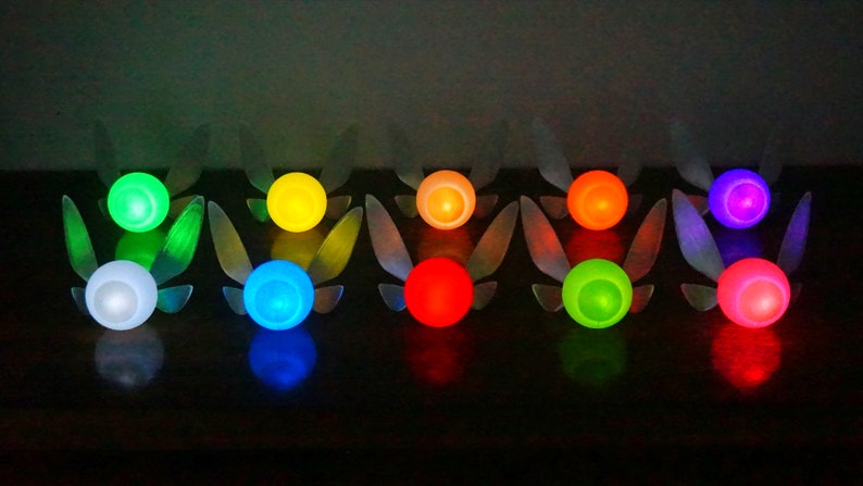 May include: Ten glowing fairy lights in various colors, including white, green, blue, yellow, red, and purple. Each light has a pair of wings.