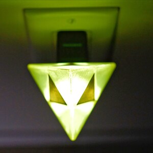 May include: A green glass pyramid-shaped night light plugged into an electrical outlet.