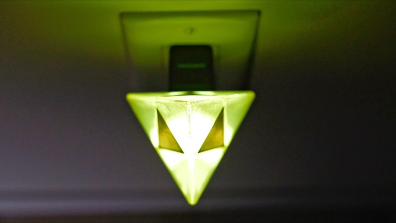 May include: A green glass pyramid-shaped night light plugged into an electrical outlet.