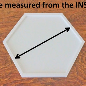 Puede incluir: Bandeja hexagonal blanca con una flecha negra apuntando diagonalmente hacia el interior. El texto "Size measured from the INSIDE" est&aacute; por encima de la bandeja.