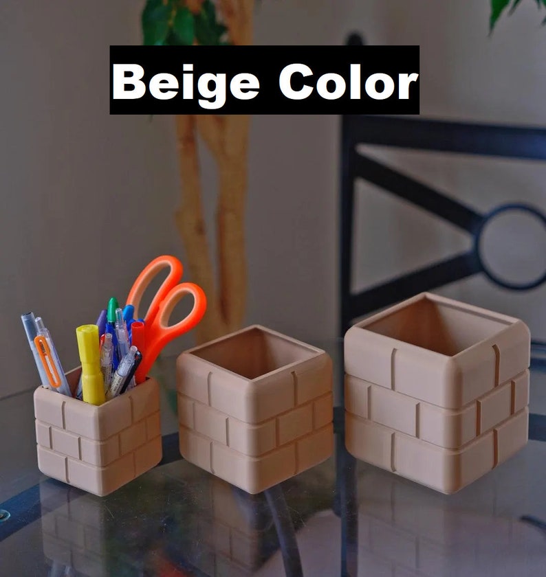 Pu&ograve; includere: Tre organizzatori da scrivania beige con motivo a mattoni, uno dei quali contiene una variet&agrave; di penne e forbici. Gli organizzatori sono su un tavolo di vetro.