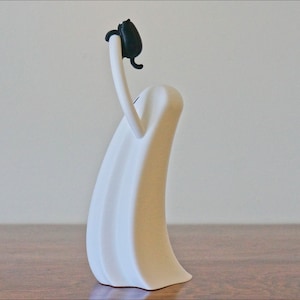 Peut inclure: Sculpture en c&eacute;ramique blanche repr&eacute;sentant une personne avec une t&ecirc;te noire et les bras lev&eacute;s au-dessus de la t&ecirc;te.