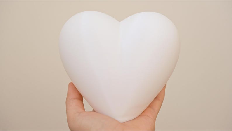 May include: A white heart-shaped object held in a hand.