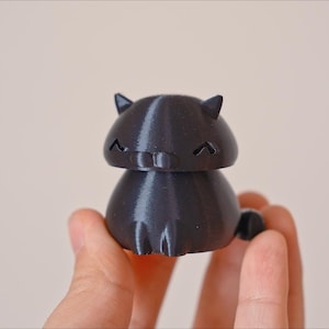 Peut inclure: Une figurine de chat noire imprim&eacute;e en 3D avec une expression mignonne. Le chat a une petite queue et est assis sur ses pattes arri&egrave;re.