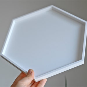 May include: A white hexagonal tray with a smooth surface. The tray is made of a sturdy material and has a modern design.