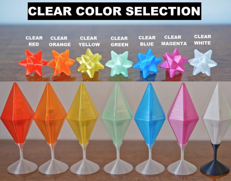 May include: A selection of eight clear plastic diamond-shaped ornaments in various colors, including red, orange, yellow, green, blue, magenta, and white. The ornaments are displayed on a white surface with a black background.