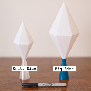 May include: Two white geometric sculptures, one small and one large, with a Sharpie marker for size comparison. The larger sculpture has a blue base and a brown accent. The smaller sculpture has a clear base. Text on the image reads "Small Size" and "Big Size".