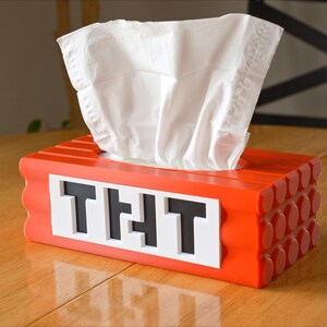 May include: Red tissue box shaped like a Minecraft block with the word "THT" on the front.