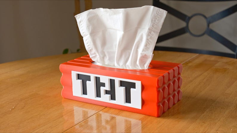 May include: Red tissue box shaped like a Minecraft block with the word "THT" on the front.