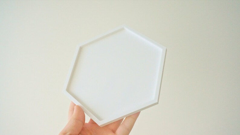 Puede incluir: Una bandeja hexagonal blanca con una superficie lisa. La bandeja est&aacute; hecha de un material duradero y es perfecta para exhibir objetos peque&ntilde;os o servir aperitivos.