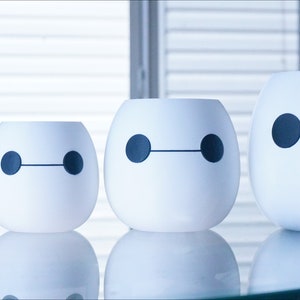 Pu&ograve; includere: Quattro vasi in ceramica bianca di diverse dimensioni, ognuno con un design in bianco e nero di Baymax, il robot del film Disney Big Hero 6.