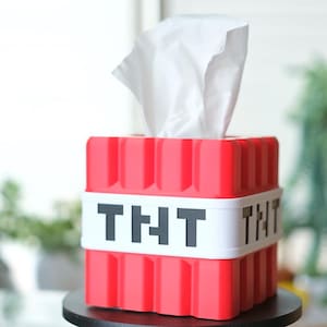 K&ouml;nnte beinhalten: Rote und wei&szlig;e Tissuebox in Form eines Minecraft TNT-Blocks. Die Box hat den Schriftzug "TNT" auf der Vorderseite.