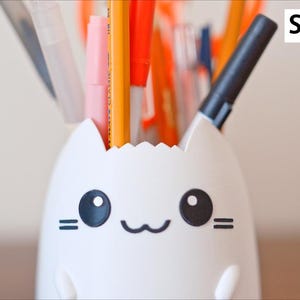May include: A white cat-shaped desk organizer filled with pens and pencils. The organizer has a smiling face with black eyes and whiskers. The text "Spiky Hair" is in the upper right corner.