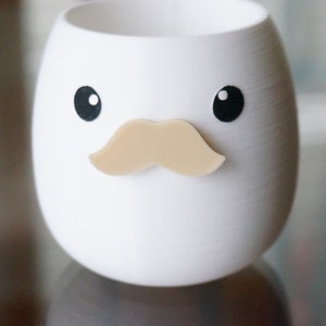 May include: White ceramic planter shaped like an egg with black eyes and a brown mustache.