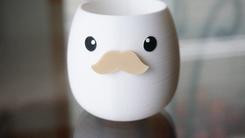 May include: White ceramic planter shaped like an egg with black eyes and a brown mustache.