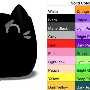 May include: A digital rendering of a black cat-shaped object with white eyes and a frown. The image includes a color chart with various color options for the object.