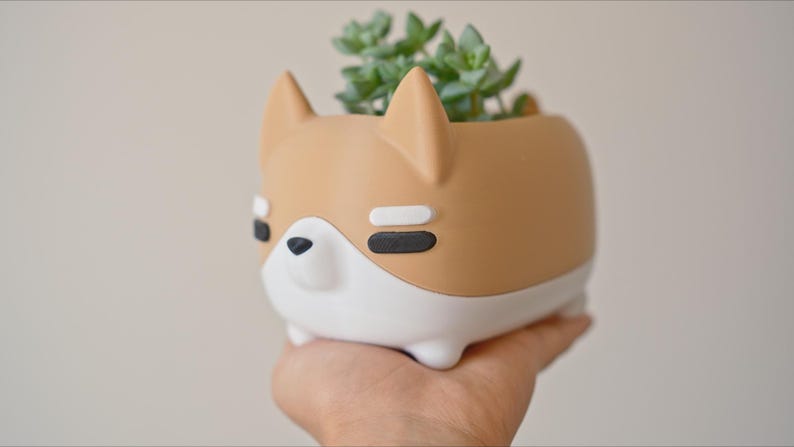 May include: A brown and white ceramic planter shaped like a dog with a small succulent plant growing inside.