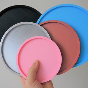 May include: Set of five round trays in different sizes and colors. The trays are black, silver, pink, brown, and blue.