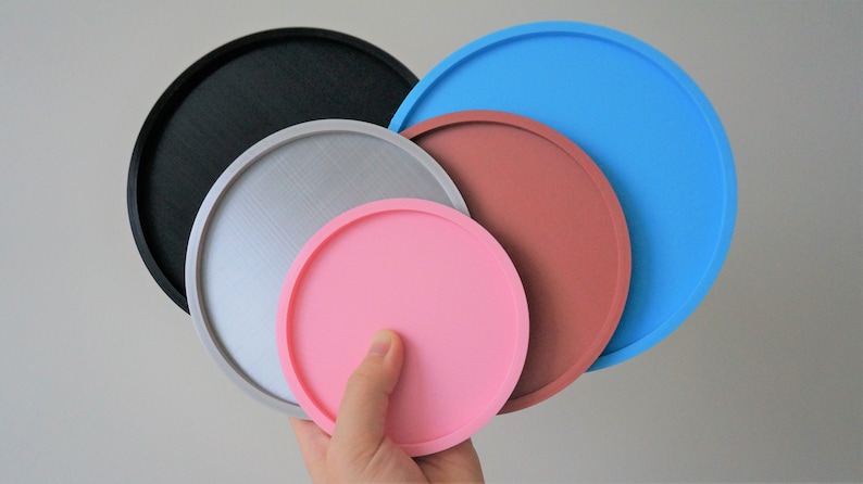 May include: Set of five round trays in different sizes and colors. The trays are black, silver, pink, brown, and blue.