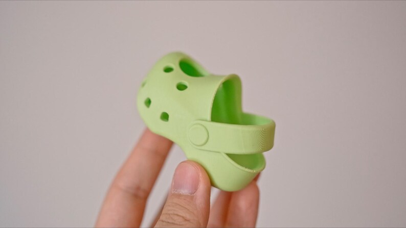 May include: A light green silicone shoe charm with a strap and holes.