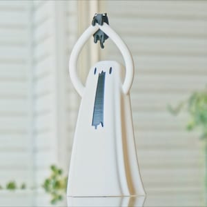 Peut inclure: Figurines en c&eacute;ramique blanche repr&eacute;sentant un fant&ocirc;me tenant un autre petit fant&ocirc;me au-dessus de sa t&ecirc;te. Les yeux et la bouche des fant&ocirc;mes sont noirs.