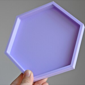 May include: A light purple hexagonal tray with a smooth surface. The tray is made of a durable material and is perfect for displaying small items.