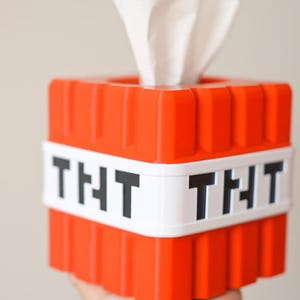 K&ouml;nnte beinhalten: Eine rote und wei&szlig;e Tissuebox in Form eines Minecraft TNT-Blocks. Die Box hat das Wort "TNT" in Schwarz aufgedruckt.