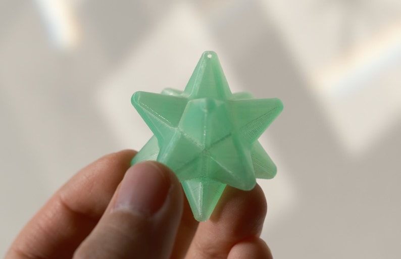 May include: A light green, 3D printed, star-shaped ornament with a hole at the top for hanging.