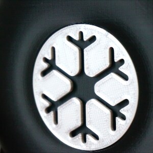 May include: A black round object with a silver snowflake design.