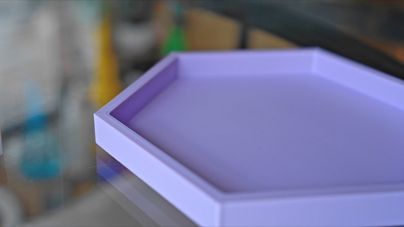 May include: A light purple hexagonal tray with a raised edge. The tray is made of a smooth, textured material.