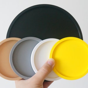 May include: Set of six round coasters in various colors, including black, brown, gray, white, and yellow. The coasters are made of a smooth, durable material and are perfect for protecting surfaces from scratches and spills.
