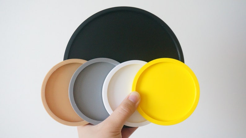 May include: Set of six round coasters in various colors, including black, brown, gray, white, and yellow. The coasters are made of a smooth, durable material and are perfect for protecting surfaces from scratches and spills.