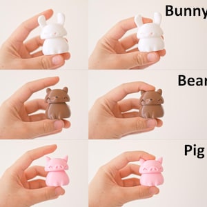Peut inclure: Trois petites figurines d'animaux peintes &agrave; la main. Un lapin blanc, un ours brun et un cochon rose. Chaque figurine a un visage mignon et de style dessin anim&eacute;.