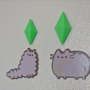 May include: Two green diamond-shaped magnets and two grey cat stickers on a white refrigerator.